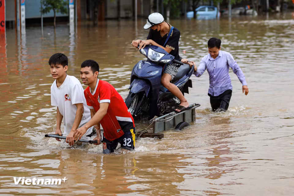 Gần đó tại khu vực cầu Ngà có đoạn ngập sâu khiến việc di chuyển của người dân gặp nhiều khó khăn. (Ảnh: Hoài Nam/Vietnam+)