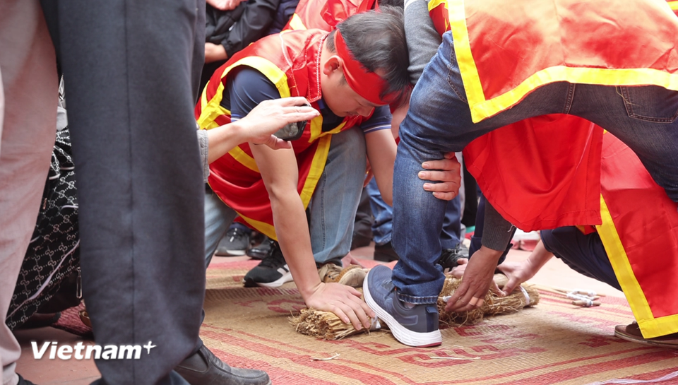 Cuộc thi không trao giải chung cuộc, mà trao phần thắng cho 3 công đoạn quan trọng: Đội kéo lửa nhanh nhất, đội lấy nước nhanh nhất và đội thổi cơm ngon nhất. Trong hình là phần thi kéo lửa bằng cách đè hai thanh giang lên cật tre và bùi nhùi rồi giật mạnh để tạo ma sát sinh ra lửa. (Ảnh: Minh Anh/Vietnam+)