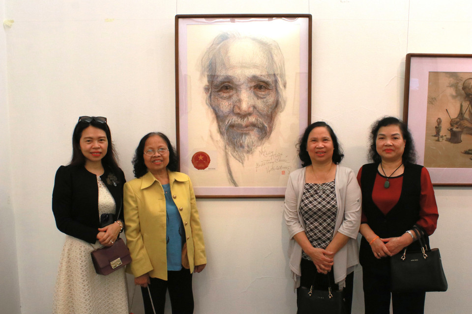 3 con và cháu gái cố họa sỹ Bùi Trang Chước chụp cùng chân dung ông do Lê Lam vẽ. Họa sỹ Lê Lam cùng với họa sỹ Ngọc Linh (Vi Văn Bích, sinh năm 1930), đều là những học trò đã tham gia bảo vệ thầy Bùi Trang Chước trong cuộc đấu tranh xác nhận tác giả thật sự của mẫu quốc huy Việt Nam. (Ảnh: Minh Anh/Vietnam+)
