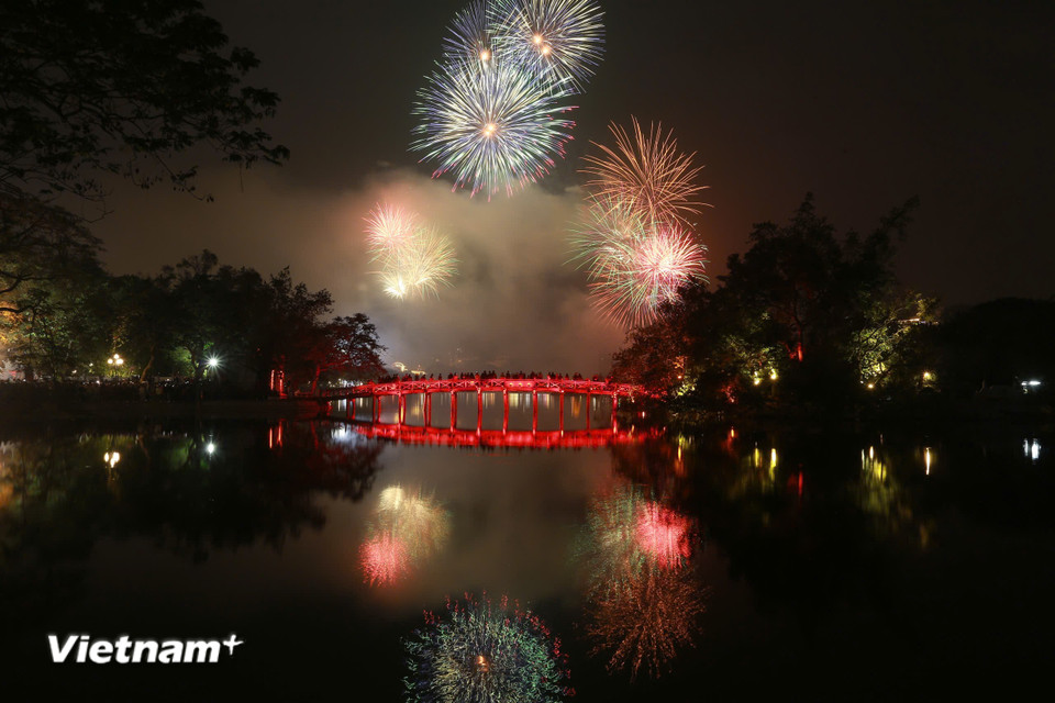 Chùm pháo hoa rực rỡ màu sắc soi bóng mặt hồ. (Ảnh: PV/Vietnam+)
