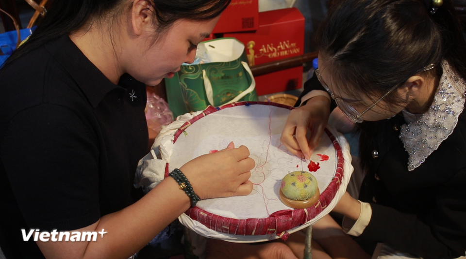 Du khách có thể trao đổi, giao lưu với những người phụ trách thêu áo tỉ mỉ, khéo léo. (Ảnh: Minh Anh/Vietnam+)