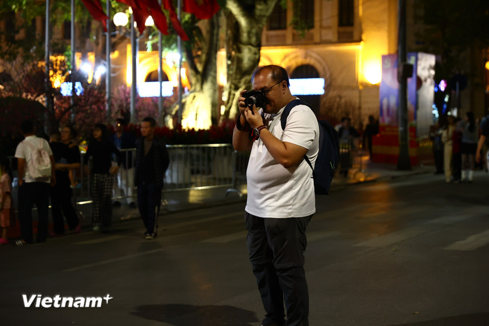 Du khách thích thú ghi lại nhiều khoảnh khắc đời sống trên phố đi bộ nhộn nhịp nhất Thủ đô Hà Nội. (Ảnh: Minh Anh/Vietnam+)