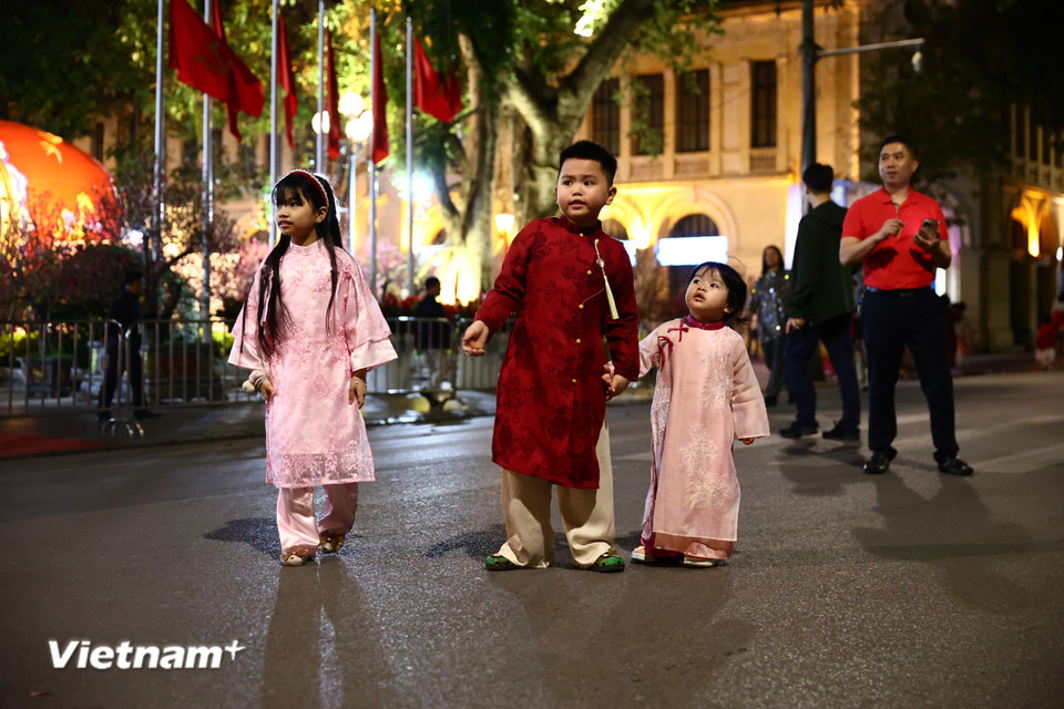 Tối 16/2 tức 29 Tết, nhiều người dân đã xúng xính áo dài, "thả dáng" tại Phố đi bộ Hồ Gươm để chờ đón hoạt động bắn pháo hoa. (Ảnh: Minh Anh/Vietnam+)