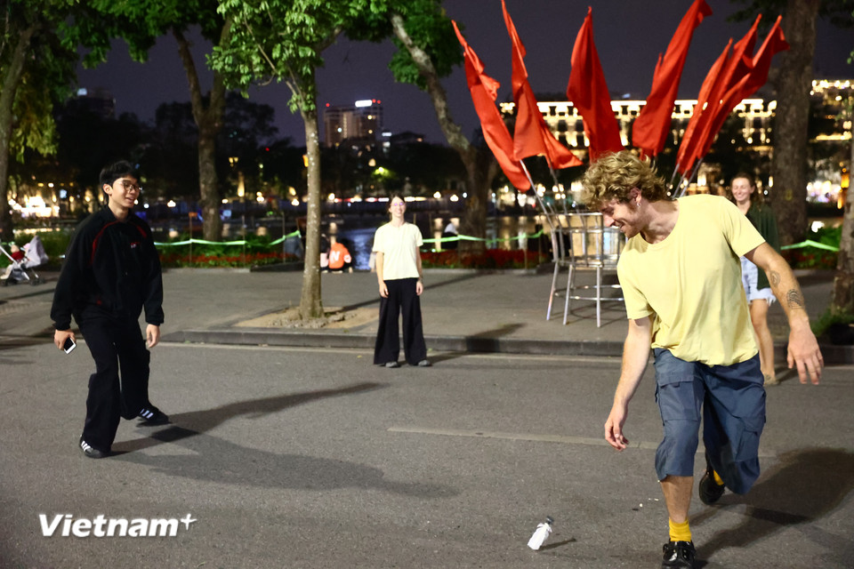 Một nhóm người nước ngoài chơi đá cầu - một hoạt động giải trí quen thuộc tại Hồ Gươm, vui vẻ mời thêm người qua đường cùng tham gia. (Ảnh: Minh Anh/Vietnam+)