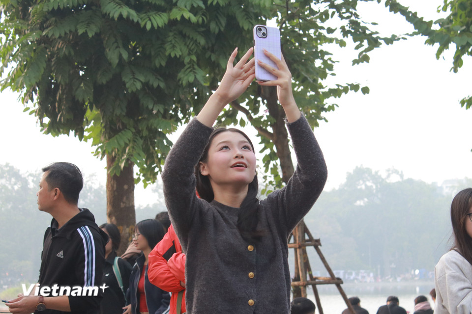 Du khách trẻ tuổi bất ngờ bắt gặp đoàn diễu hành... (Ảnh: Minh Anh/Vietnam+)