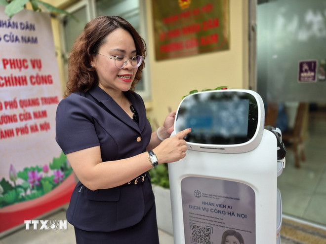 Bà Trịnh Ngọc Trâm, Phó Chủ tịch UBND phường Cửa Nam giới thiệu những tính năng ưu việt của Robot AI. (Ảnh: Nguyễn Thắng/TTXVN) ttxvn-ha-noi-dua-robot-vao-phuc-vu-hanh-chinh-cong-cach-lam-sang-tao-tu-co-so2.jpg