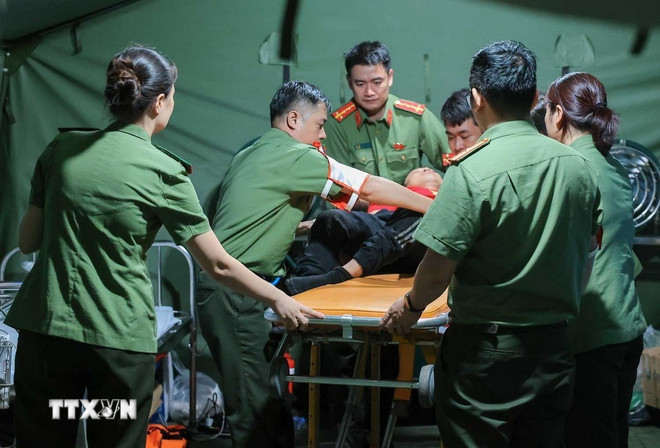 Các bác sỹ của Công an Hà Nội khẩn trương sơ cứu cho người dân bị ngã, có hiện tượng co giật khi đi xem lễ diễu binh, diễu hành tại trạm y tế dã chiến phố Liễu Giai. (Ảnh: Hoàng Hiếu/TTXVN) ttxvn-ho-tro-y-te-a80-2.jpg