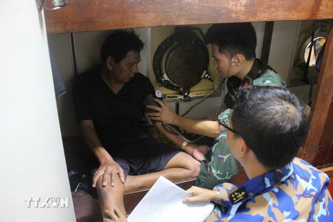 Doctors and nurses on ship 711 examine and care for seriously ill fishermen brought from Truong Sa to shore. (Photo: VNA) ttxvn-kip-thoi-dua-2-ngu-dan-bi-benh-nang-tu-truong-sa-ve-bo-an-toan2.jpg