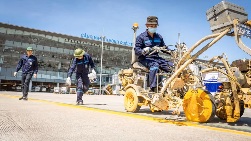 Công nhân thực hiện công tác sơn kẻ tín hiệu, vị trí đỗ máy bay, đảm bảo đúng tiêu chuẩn an toàn bay dưới thời tiết nắng như đổ lửa. (Ảnh: Phan Công/Vietnam+)