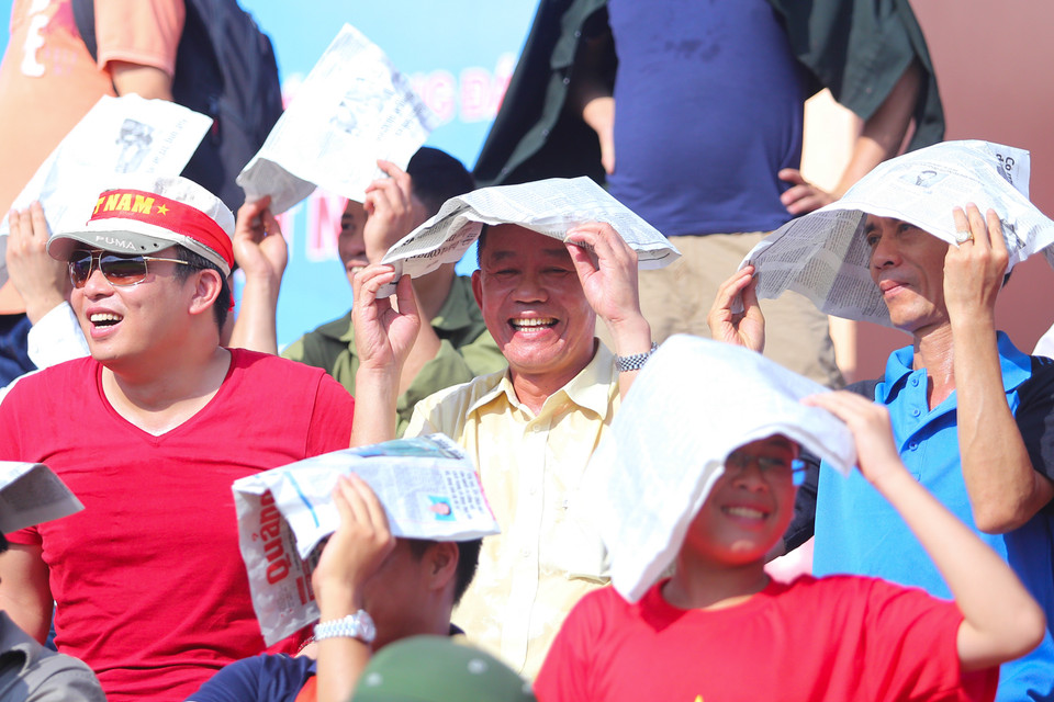 Cổ động viên phải tìm mọi cách để chống lại nắng nóng lúc 4 giờ chiều. (Ảnh: Minh Chiến/Vietnam+)