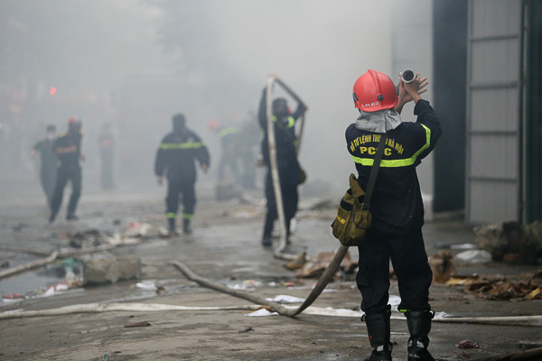 Các chiến sĩ cứu hỏa cố gắng ngăn chặn không cho ngọn lửa lan rộng. (Ảnh: Minh Chiến/Vietnam+)