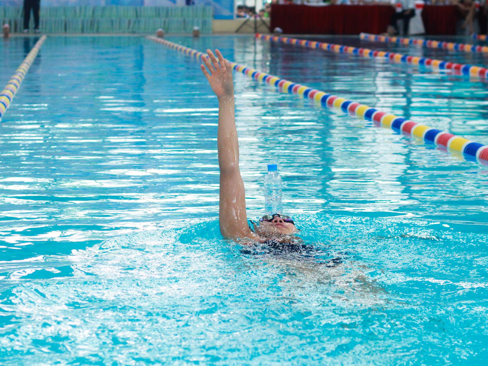 “Tiểu tiên cá” thể hiện kĩ năng “độc” để chai nước lên trán và bơi ngửa. (Ảnh: Hiếu Lương/Vietnam+)