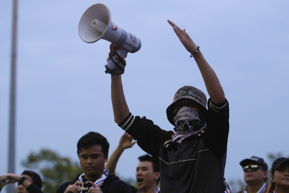 Thủ lĩnh của Hội cổ động viên Thái Lan tại Mỹ Đình điều khiển lực lượng của mình bằng loa và các hiệu lệnh tay rất rõ ràng. Cùng thời điểm đó, mới có hơn 100 người của Hội cổ động viên Việt Nam trên khán đài. (Ảnh: Minh Chiến/Vietnam+)