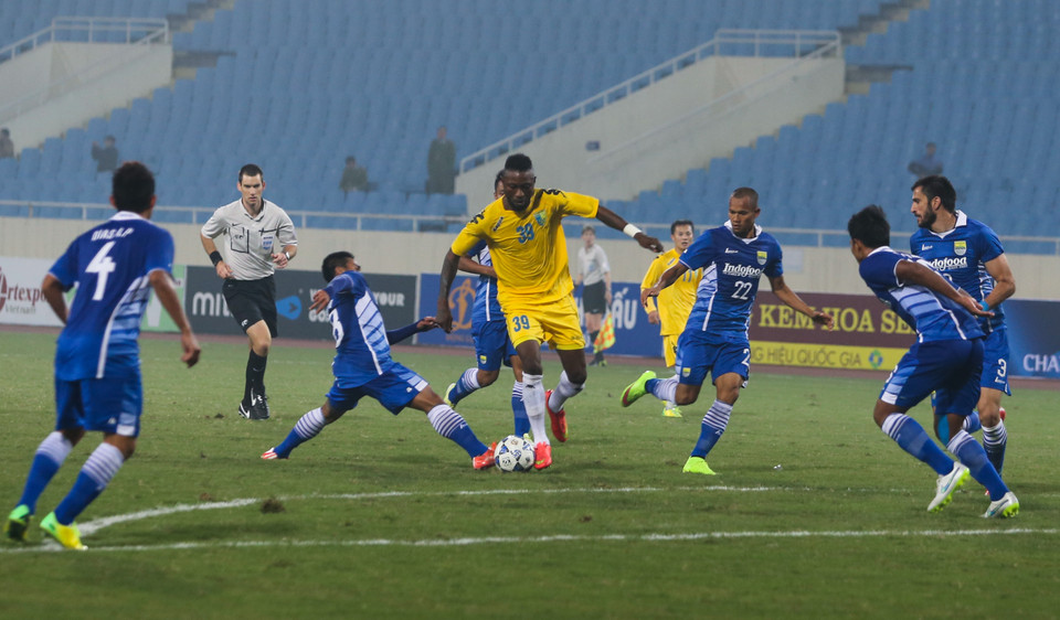 Samson (áo vàng giữa) trong vòng vây của 6 cầu thủ Persib, anh là người hoạt động năng nổ nhất trên hàng công Hà Nội T&amp;T. (Ảnh: Hiếu Lương/VietnamPlus)