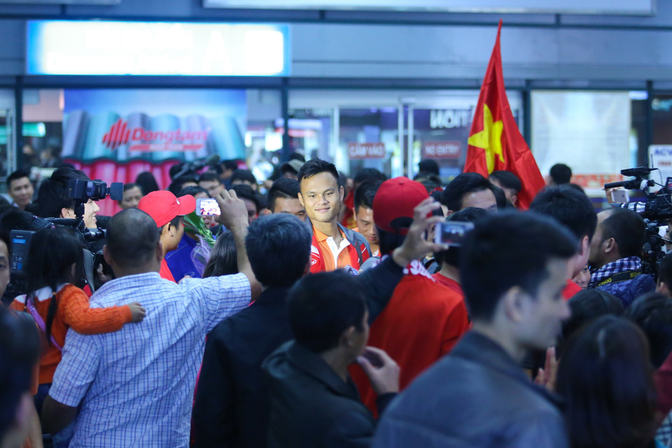 Tuyển thủ Việt Nam bị vây kín trong vòng tay của người hâm mộ sau khi đặt chân xuống Nội Bài. (Ảnh: Minh Chiến/Vietnam+) Đội tuyển quốc gia Việt Nam đã bị hàng trăm “fan cuồng" vây kín ngay khi vừa đặt chân xuống sân bay Nội Bài, Hà Nội vào hồi 18 giờ tối nay (8/12).Hành trình di chuyển mệt mỏi của tuyển Việt Nam bắt đầu từ Malaysia, trung chuyển qua Thành phố Hồ Chí Minh trước khi trở về Hà Nội vào chiều tối nay. Chiến thắng 2-1 trước Malaysia ở bán kết lượt đi AFF Suzuki Cup 2014 đã giúp thầy trò ông Toshiya Miura đặt một chân vào chung kết. Đó là lý do giải thích cho bầu không khí rực lửa ở Nội Bài cách đây ít giờ.