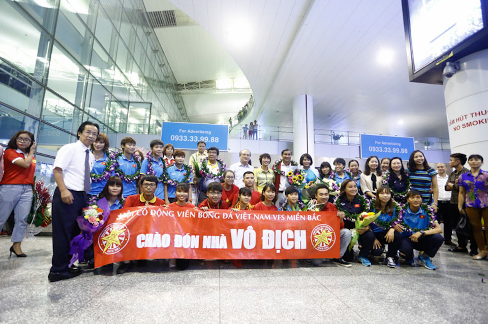 Các cầu thủ nữ cùng chức vô địch đã trở về trong vòng tay người hâm mộ. Dù tuyển nữ ra khỏi sân bay chậm một giờ, vẫn có rất nhiều cổ động viên nhẫn nại ở lại chào đón “những cô gái vàng”. (Ảnh: Tá Hiển/Vietnam+)