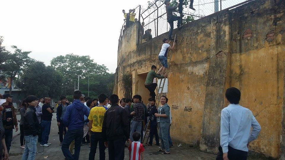 Nhân lúc lực lượng an ninh lơ là, họ liên tiếp dùng thang gỗ vượt qua bức tường cao hơn 5m có hàng rào thép gai để vào sân. (Ảnh: Minh Chiến/Vietnam+)
