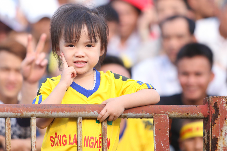 Một cổ động viên nhí theo cha tới sân cổ vũ đội bóng quê hương. (Ảnh: Minh Chiến/Vietnam+)
