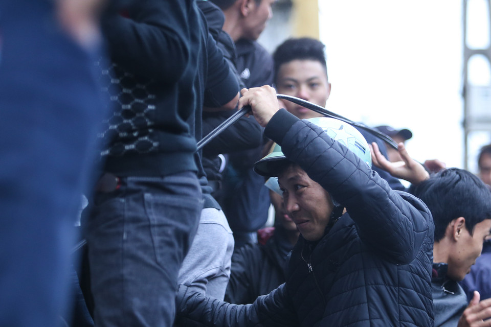 Một cổ động viên dùng tay trần vén dây diện để chen vào mua vé. (Ảnh: Minh Chiến/Vietnam+)