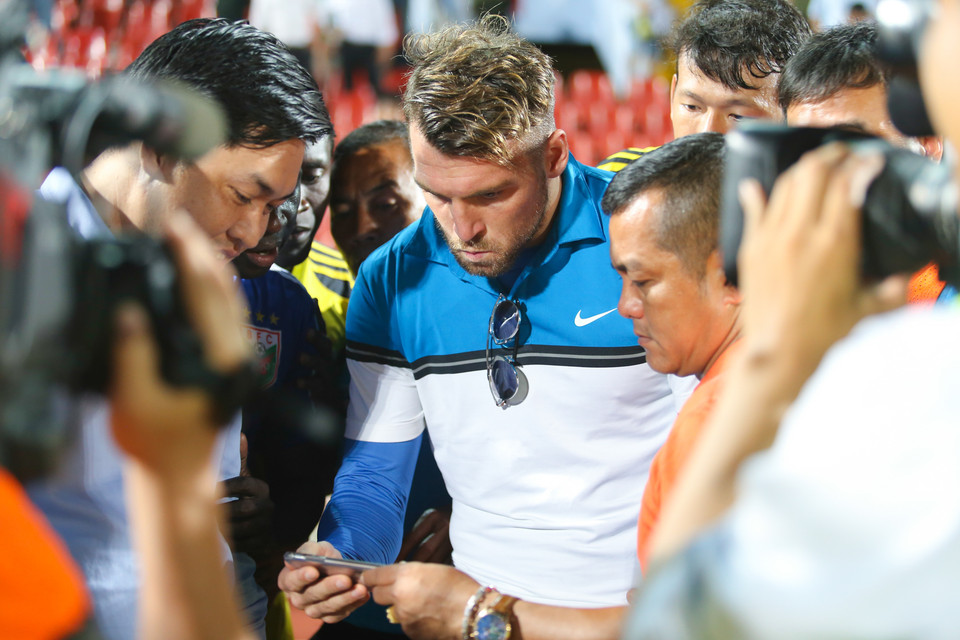 Marco Simic cầm iPphone mở chương trình tường thuật trực tiếp cho các cầu thủ Becamex Bình Dương theo dõi trận đấu của Thanh Hóa. Trước đó, tin thất bại của Hà Nội T&amp;T đã được chuyển về. (Ảnh: Minh Chiến/Vietnam+) Các cầu thủ Becamex Bình Dương đã vây quanh chiếc điện thoại trong tay ngoại binh Marco Simic sau tiếng còi kết thúc trận hòa 0-0 với Hải Phòng. Họ nhận tin vô địch qua điện thoại trước khi ồ lên ăn mừng vì chiến thắng.