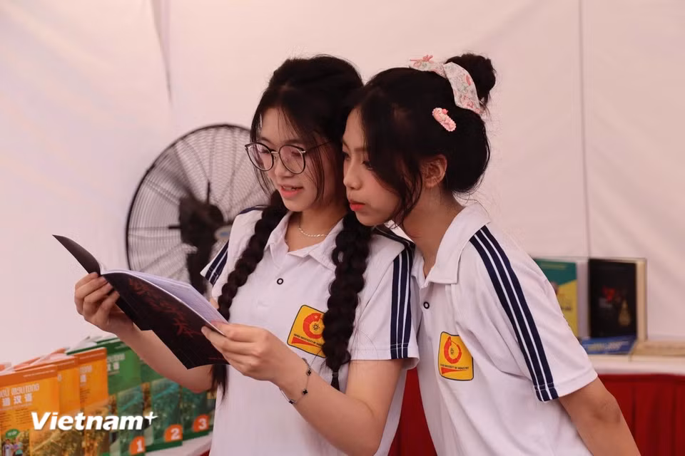 Nhiều sinh viên dành thời gian đọc và tìm hiểu các ấn phẩm được trưng bày tại khu vực sách. (Ảnh: Minh Vũ/Vietnam+)