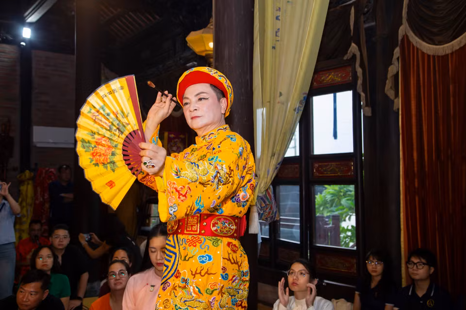 Đồng thầy Nguyễn Đức Hiển hóa thân vào hình tượng Quan Hoàng Mười đề thơ trên quạt. (Ảnh: PV/Vietnam+)