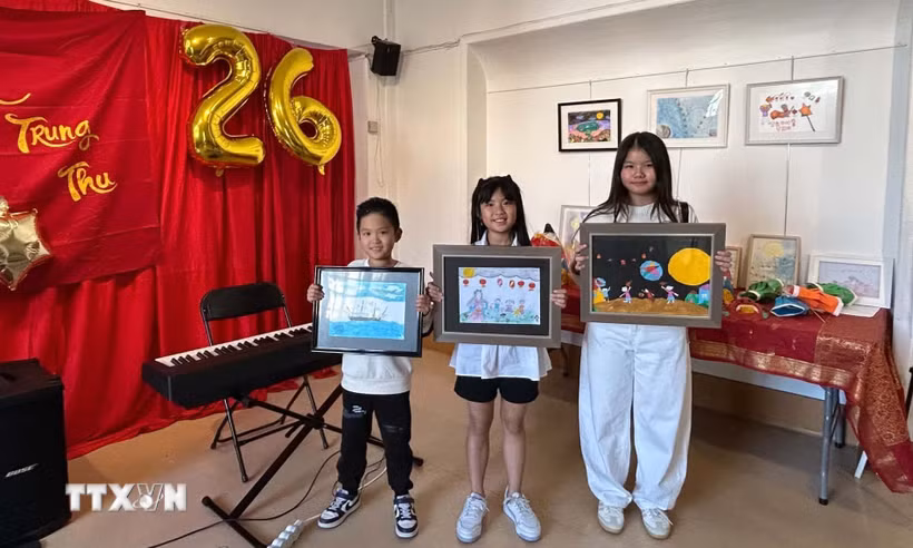 Em François Phạm, 8 tuổi (bên trái), cùng các thí sinh giới thiệu những tác phẩm tham dự cuộc thi vẽ tranh về Mặt Trăng. Bức tranh của François Phạm, khắc họa con tàu Việt Nam tuần tra trong đêm trăng rằm, đã giành giải Nhất nhờ thông điệp hướng về Trường Sa và những người lính đang ngày đêm gìn giữ biển, đảo quê hương. (Ảnh: Trần Đức Hùng/TTXVN)