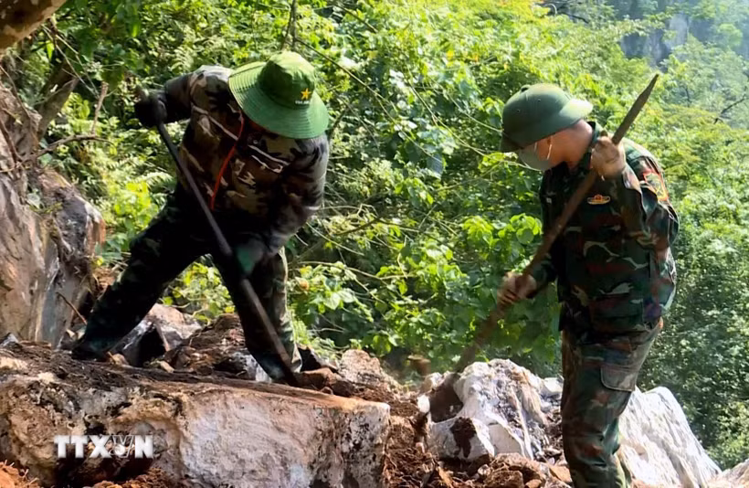 Đội quy tập hài cốt liệt sỹ dùng dụng cụ thô sơ cạy từng tảng đá, tìm kiếm hài cốt liệt sỹ. (Ảnh: TTXVN phát)