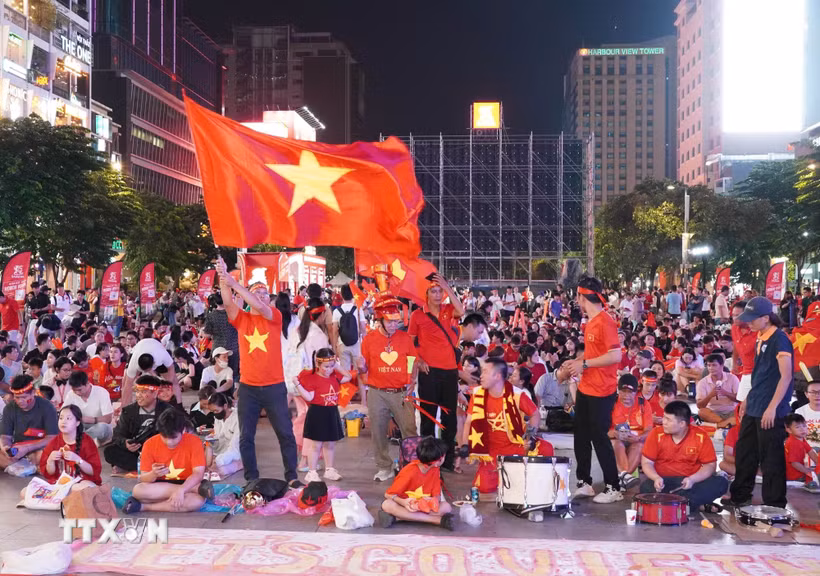 Người hâm mộ với cờ đỏ sao vàng, trống và kèn tập trung tại phố đi bộ Nguyễn Huệ, sẵn sàng tiếp lửa cho đội tuyển Việt Nam trong trận chung kết lượt đi ASEAN Hyundai Cup 2026 gặp Thái Lan. (Ảnh: Trung Tuyến/TTXVN)