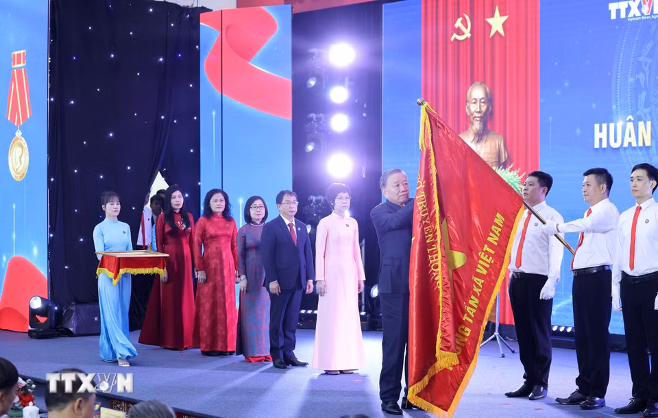 Tổng Bí thư Tô Lâm gắn Huân chương Hồ Chí Minh lên lá cờ truyền thống Thông tấn xã Việt Nam. (Ảnh: Lâm Khánh/TTXVN)