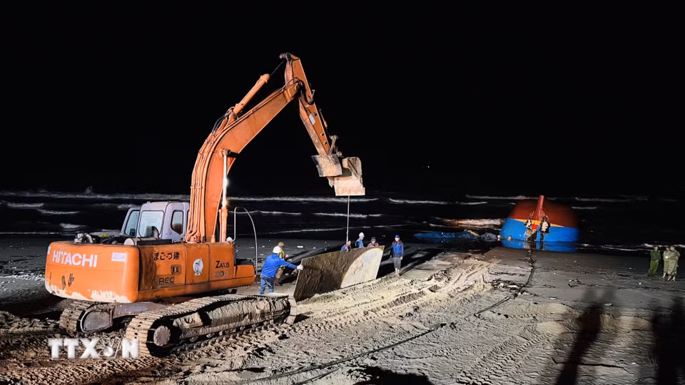 Xe máy xúc vận chuyển những tấm thép lớn để làm đường cho xe cần cẩu hạng nặng tiếp hiện trường tàu gặp nạn. (Ảnh: Nguyên Linh/TTXVN)