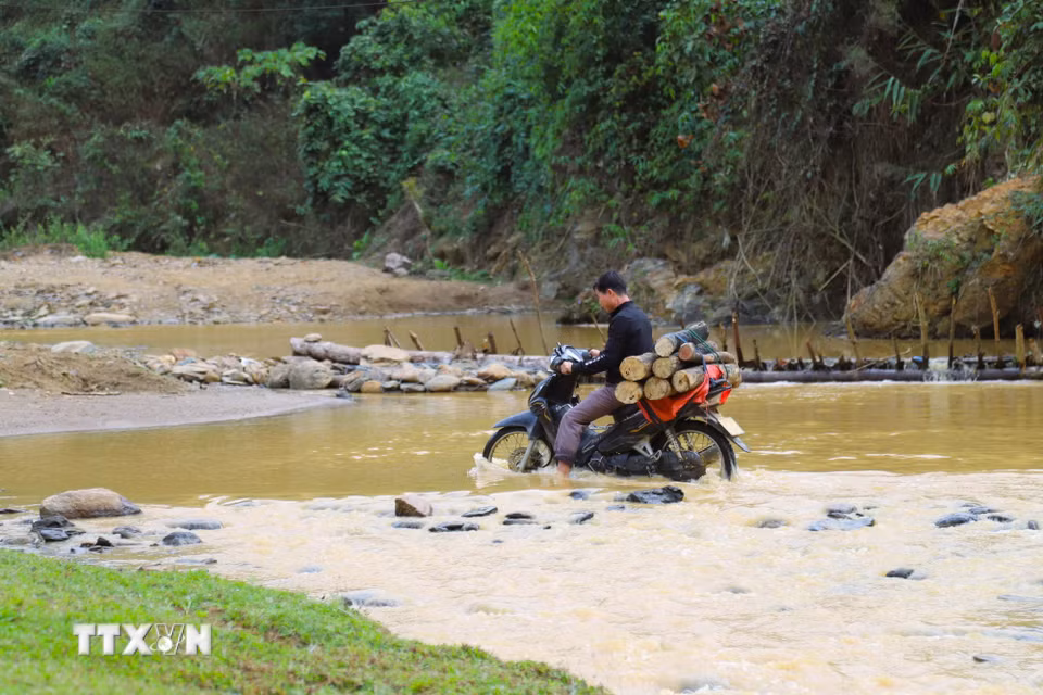 Do vị trí đền nằm đầu bản, ở chỗ linh thiêng nên người dân phải mang củi, các dụng cụ phục vụ công tác chuẩn bị lễ cúng tạ bằng xe máy từ rất sớm. Hành trình di chuyển nhiều lần phải vượt suối. (Ảnh: Xuân Tiến/TTXVN)