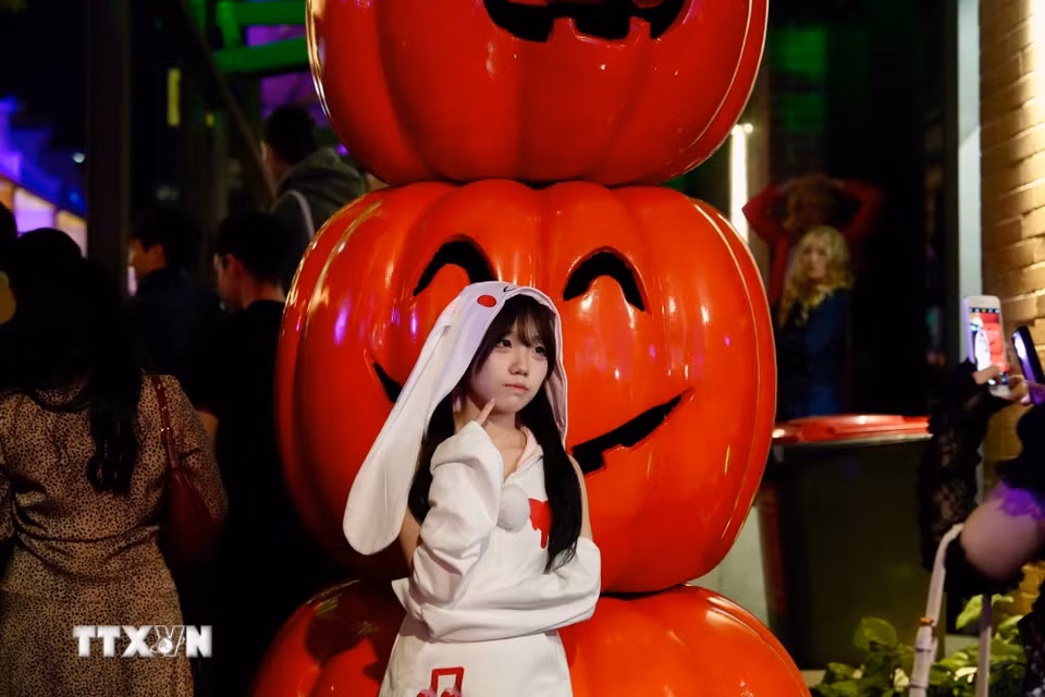 Một du khách Nhật Bản cạnh quả bí ngô Halloween. (Ảnh: Lê Đạt/TTXVN)