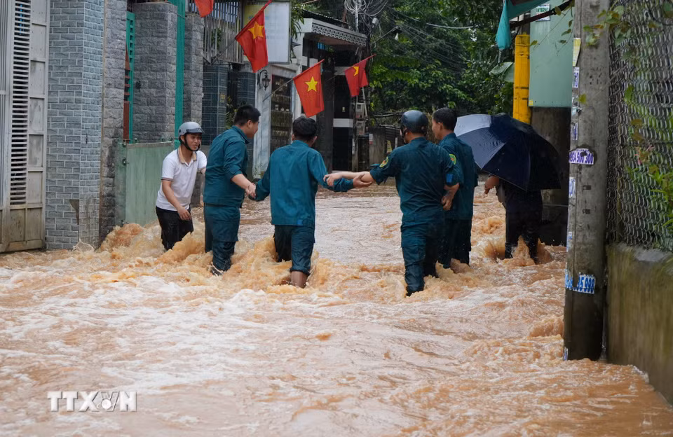 Lực lượng dân quân phường Phước Tân, thành phố Đồng Nai cố băng qua dòng nước chảy xiết để hỗ trợ người dân. (Ảnh: Lê Xuân/TTXVN)