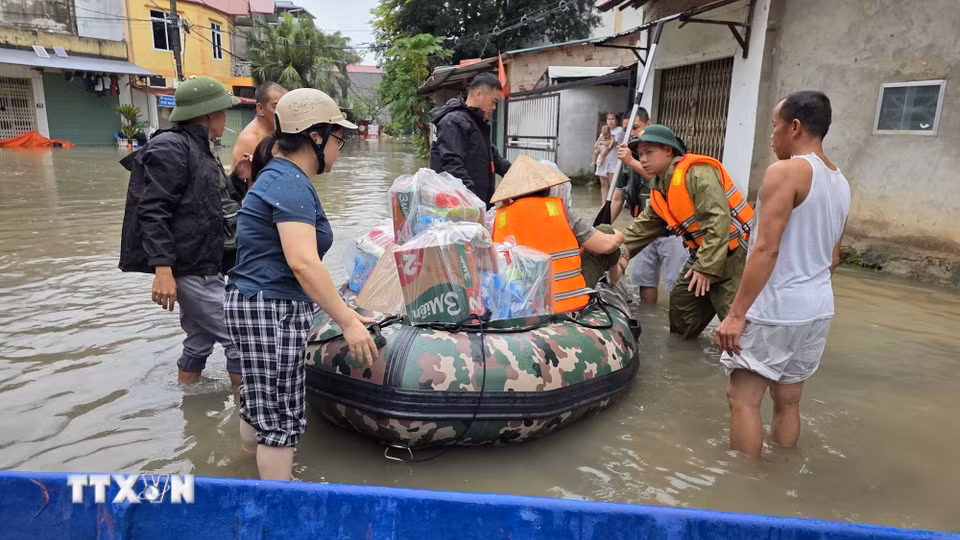 Lực lượng chức năng hỗ trợ người dân phường Tam Thanh, tỉnh Lạng Sơn vận chuyển nhu yếu phẩm vào vùng ngập lụt.(Ảnh: Quang Duy/TTXVN)