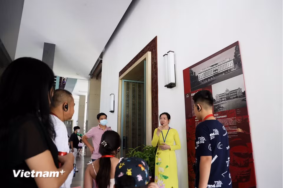 Hướng dẫn viên thuyết minh giới thiệu lịch sử hình thành Dinh Độc Lập. (Ảnh: Hồng Đạt/Vietnam+)