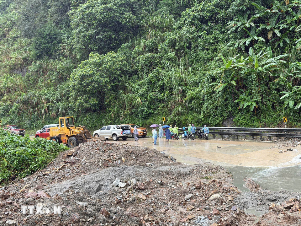 Lực lượng Cảnh sát giao thông phối hợp với chính quyền xã Đăk Plô thực hiện công tác cảnh báo để việc khắc phục sạt lở được triển khai. (Ảnh: Cao Nguyên/TTXVN)