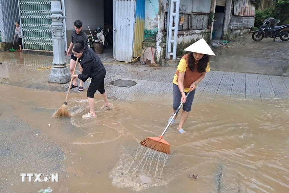 Người dân sống ở bờ Nam sông Hương, thành phố Huế dọn bùn, rác thải khi nước lũ rút sáng 29/10. (Ảnh: Nguyên Lý/TTXVN)