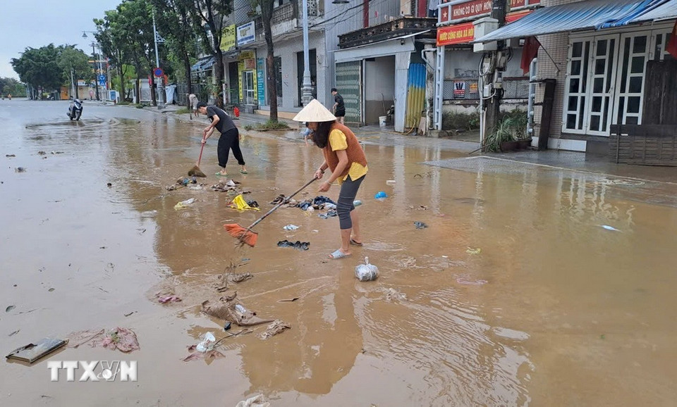 Người dân sống ở bờ Nam sông Hương, thành phố Huế dọn bùn, rác thải khi nước lũ rút sáng 29/10. (Ảnh: Nguyên Lý/TTXVN)