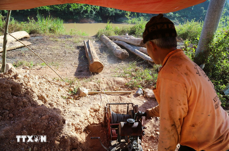 Người dân điều khiển máy tời để kéo một thân gỗ to, nặng, dài gần 4m từ bờ sông Nậm Nơn lên khu vực tập kết để cưa xẻ, sơ chế gỗ. (Ảnh: Xuân Tiến/TTXVN)