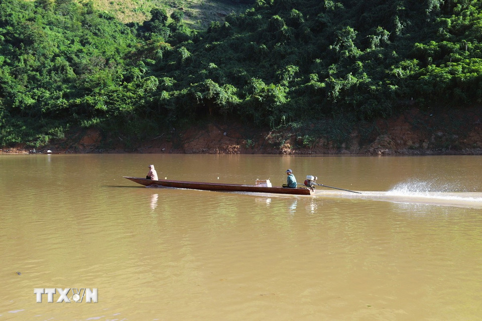 Người dân xuôi hạ nguồn sông Nậm Nơn bằng thuyền máy nhỏ để về lòng hồ thủy điện Bản Vẽ vớt gỗ. (Ảnh: Xuân Tiến/TTXVN)