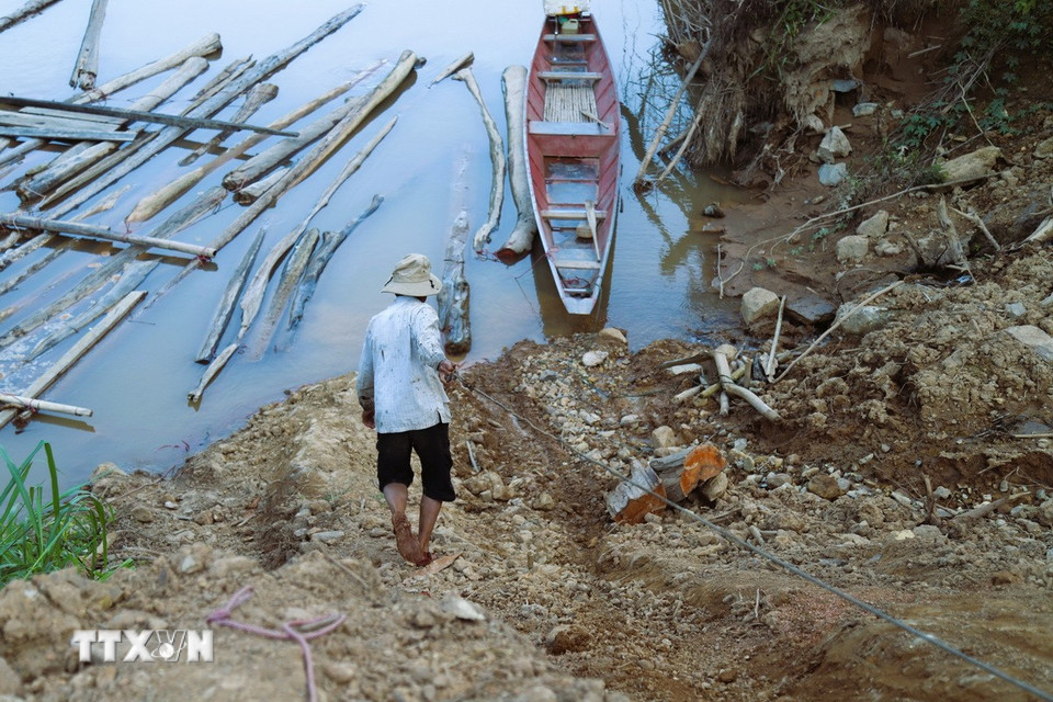 Kéo dây cáp tời xuống sông Nậm Nơn để cột vào thân gỗ trôi nổi trên mặt nước. (Ảnh: Xuân Tiến/TTXVN)