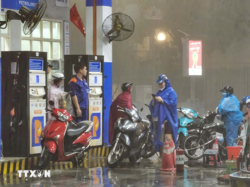 Người dân di chuyển vào trong cây xăng, để tránh mưa giông gió giật. (Ảnh: Thanh Tùng/TTXVN)