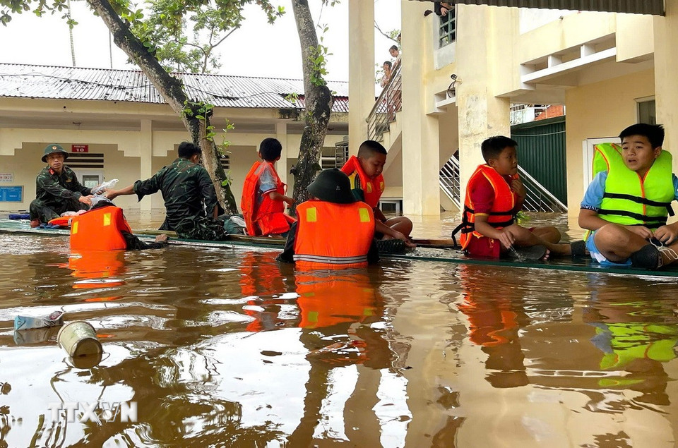 Cán bộ, chiến sỹ Bộ Chỉ huy Quân sự tỉnh Tuyên Quang đưa các học sinh ra khỏi điểm trường bị ngập sâu. (Ảnh: Đăng Ninh/TTXVN phát)