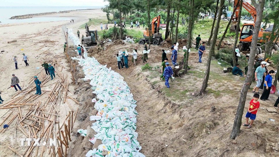 Lực lượng chức năng sử dụng bao cát để gia cố đê Hội Thống. (Ảnh: Hữu Quyết/TTXVN)