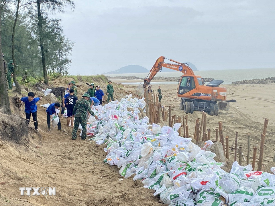 Lực lượng chức năng sử dụng bao cát để gia cố đê Hội Thống. (Ảnh: Hữu Quyết/TTXVN)