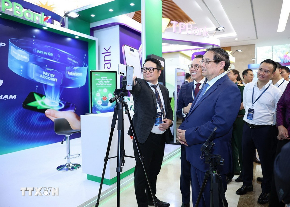 Thủ tướng Phạm Minh Chính tham quan trưng bày sản phẩm dịch vụ, ứng dụng chuyển đổi số trong hoạt động ngân hàng. (Ảnh: Dương Giang/TTXVN)