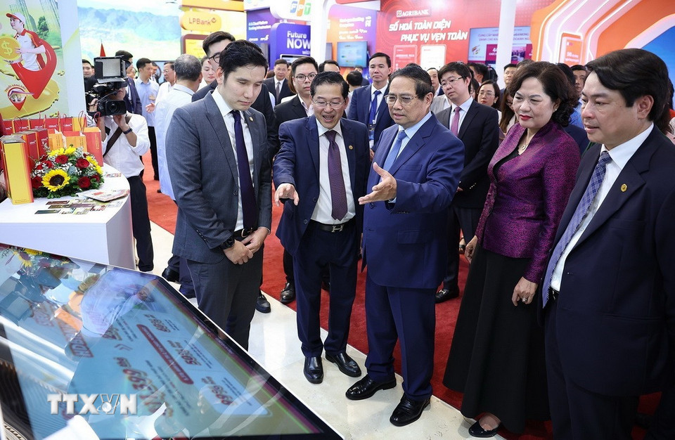 Thủ tướng Phạm Minh Chính tham quan trưng bày sản phẩm dịch vụ, ứng dụng chuyển đổi số trong hoạt động ngân hàng. (Ảnh: Dương Giang/TTXVN)