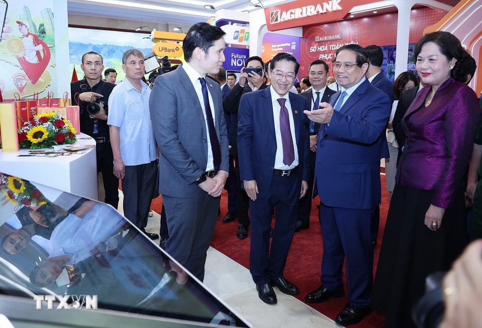 Thủ tướng Phạm Minh Chính tham quan trưng bày sản phẩm dịch vụ, ứng dụng chuyển đổi số trong hoạt động ngân hàng. (Ảnh: Dương Giang/TTXVN)