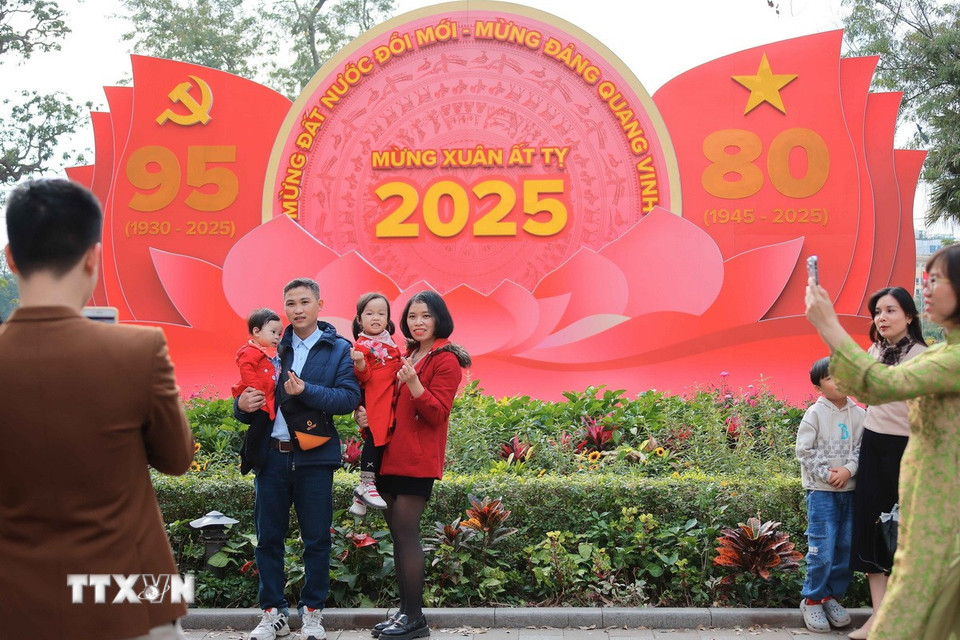 Người dân Thủ đô chụp ảnh tại khu vực quanh hồ Hoàn Kiếm - nơi bố trí nhiều panô, ápphích chào mừng 95 năm Ngày Thành lập Đảng Cộng sản Việt Nam và 80 năm thành lập Nước Cộng hòa Xã hội Chủ nghĩa Việt Nam. (Ảnh: Hoàng Hiếu/TTXVN)